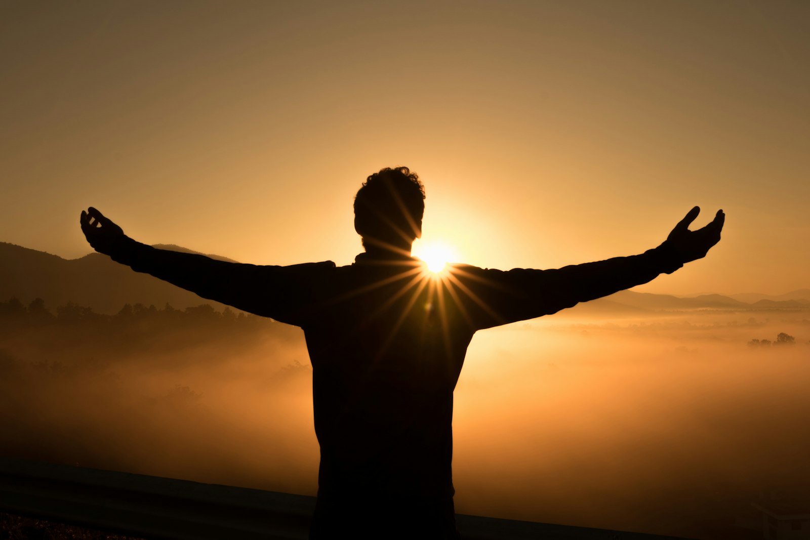 A person with outstretched arms in gentle sunset light